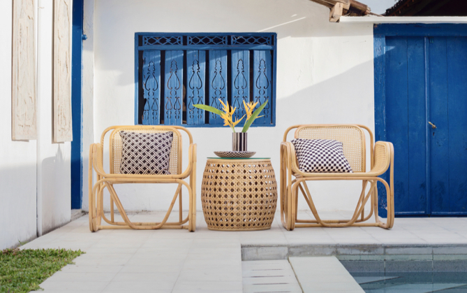A patio setting. Two seventies-style chairs and matching round side table have been placed near a swimming pool.